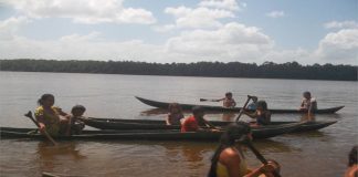 mujeres y niños reman en caonas por el Orinoco