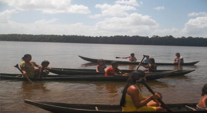 mujeres y niños reman en caonas por el Orinoco