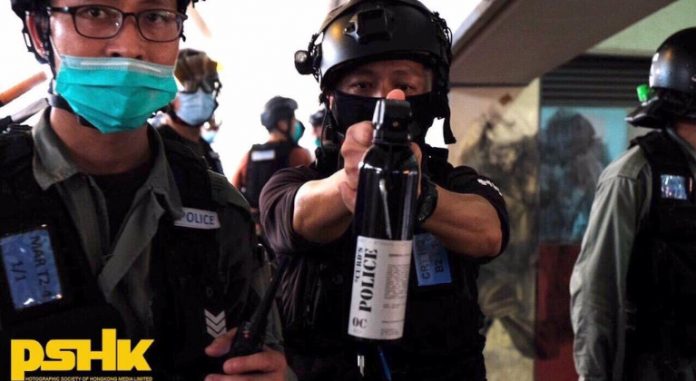 Un funcionario de la policía de Hong Kong apunta su gas pimienta a un periodista | Foto: Sociedad Fotográfica de Hong Kong
