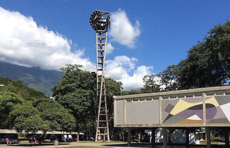 800px-Torre_del_reloj_de_tres_apoyos_en_la_Plaza_del_Rectorado,_Ciudad_Universitaria_de_Caracas_(cropped)