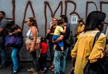 Crisis en Venezuela - personas en una cola y mural dice hambre