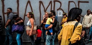 Crisis en Venezuela - personas en una cola y mural dice hambre