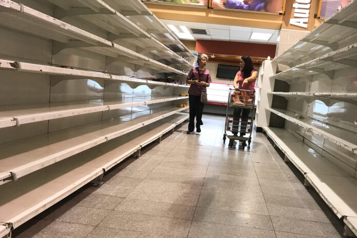 People walk past empty shelves at a supermarket in Caracas Las sanciones